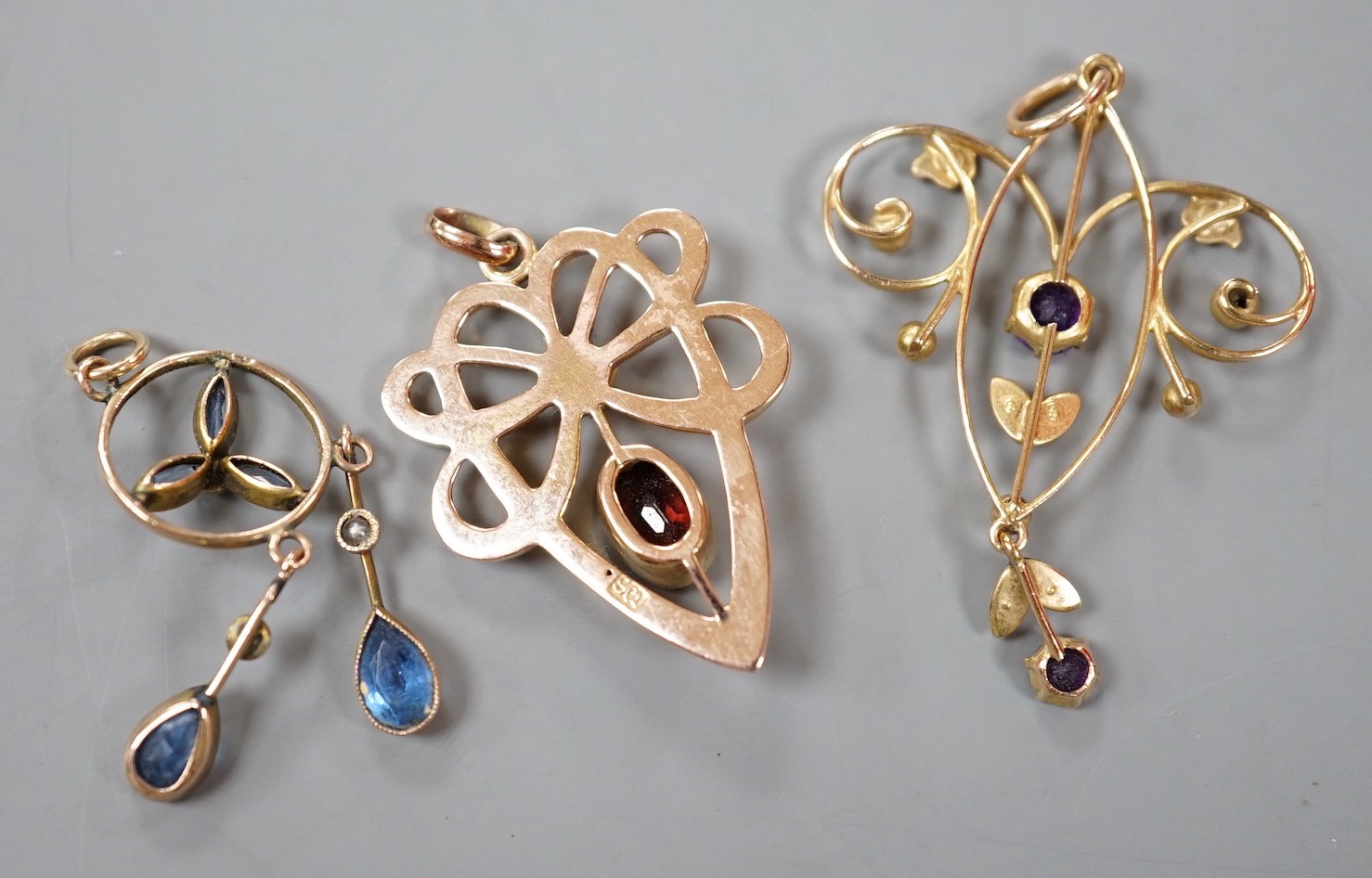 Three assorted early 20th century yellow metal and gem set pendants, including 9ct garnet and split pearl, largest overall 39mm, gross weight 5.2 grams.